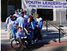 Young leaders with various disabilities standing on the steps of a building with a sign behind them that reads: Youth Leadership Forum for Students with Disabilities